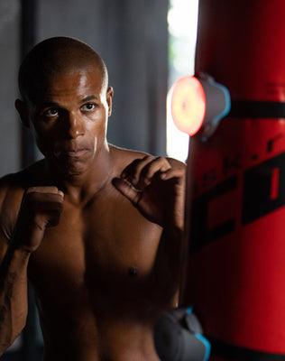 Boxer training with BlazePod light pod on a punch bag during a reflex drill